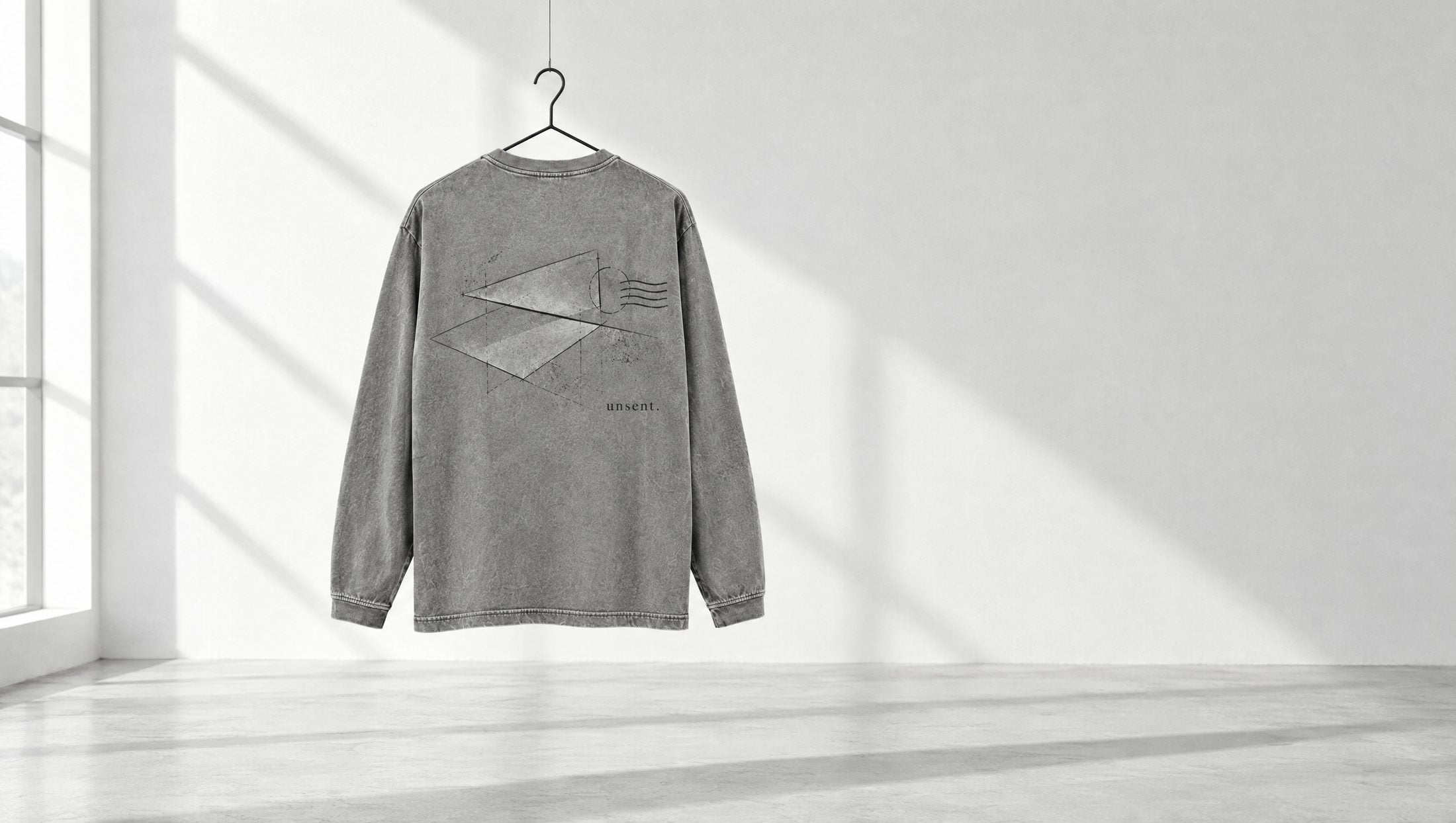 the unsent. long sleeve hanging on a wire in a white room, back facing